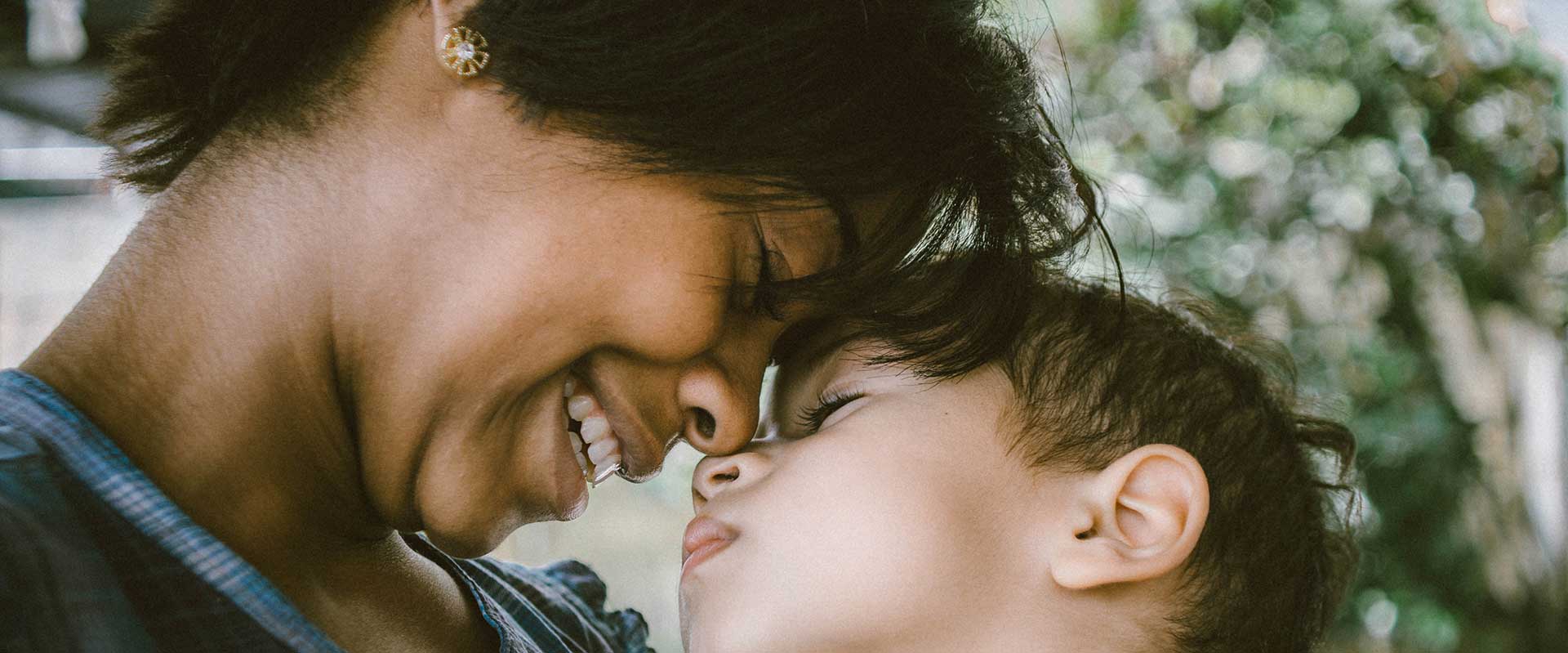 woman smiling and leaning in with her forehead rested on childs forehead