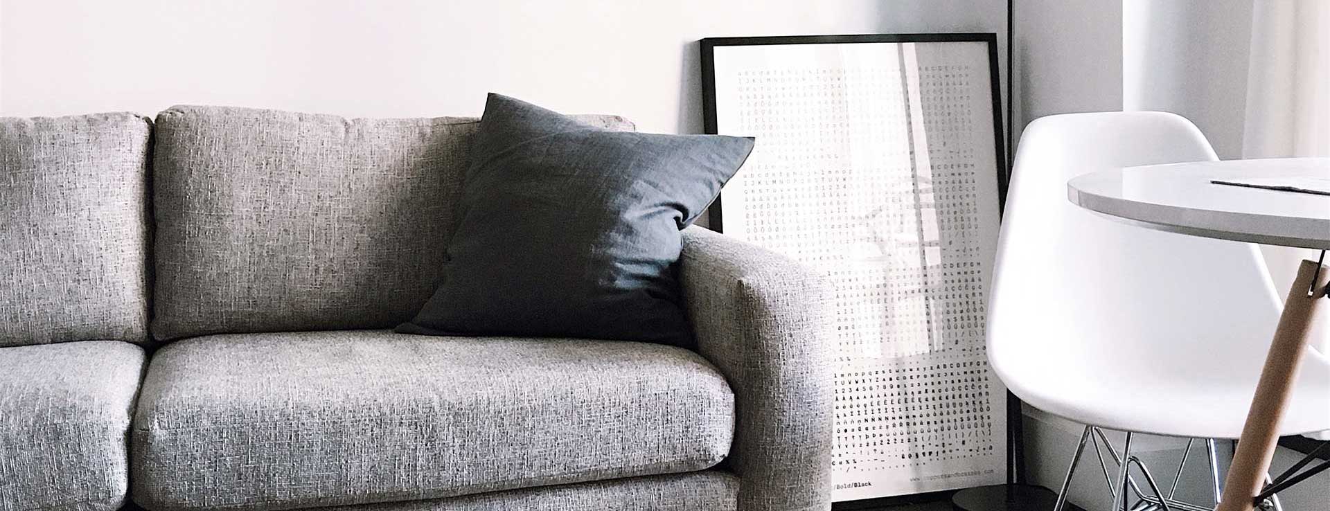 grey couch framed artwork chair and table in room